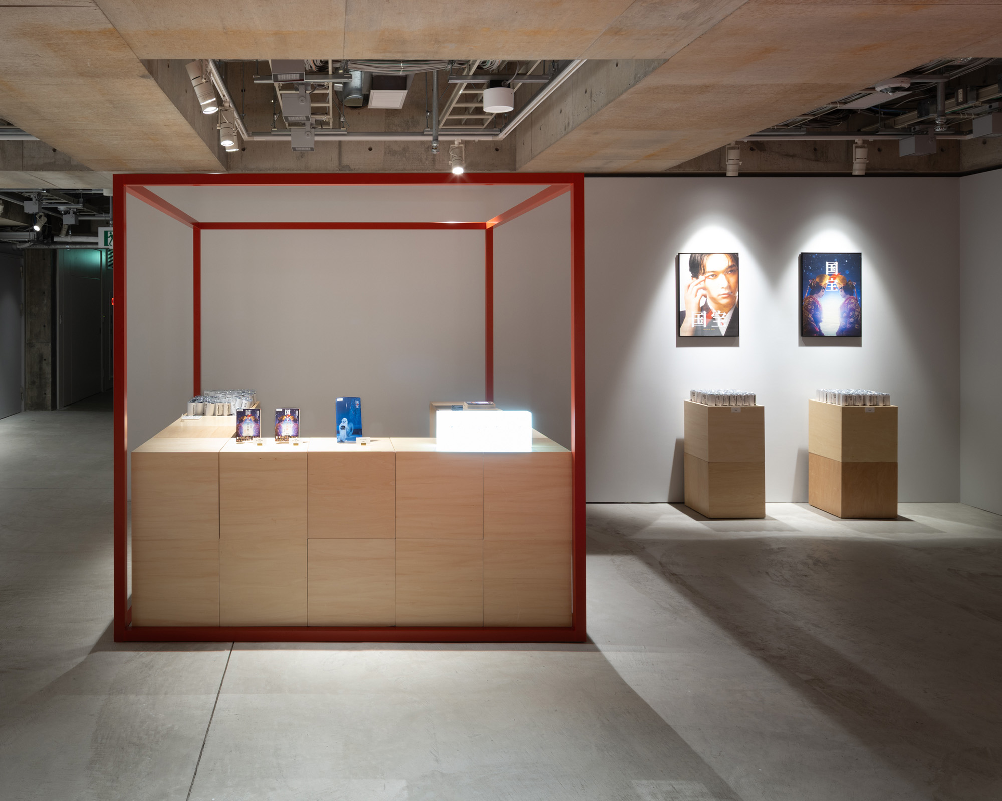 展示室内に設けられたショップスペース。木製カウンターの上に関連グッズが並び、周囲の壁面には写真作品が展示されている。